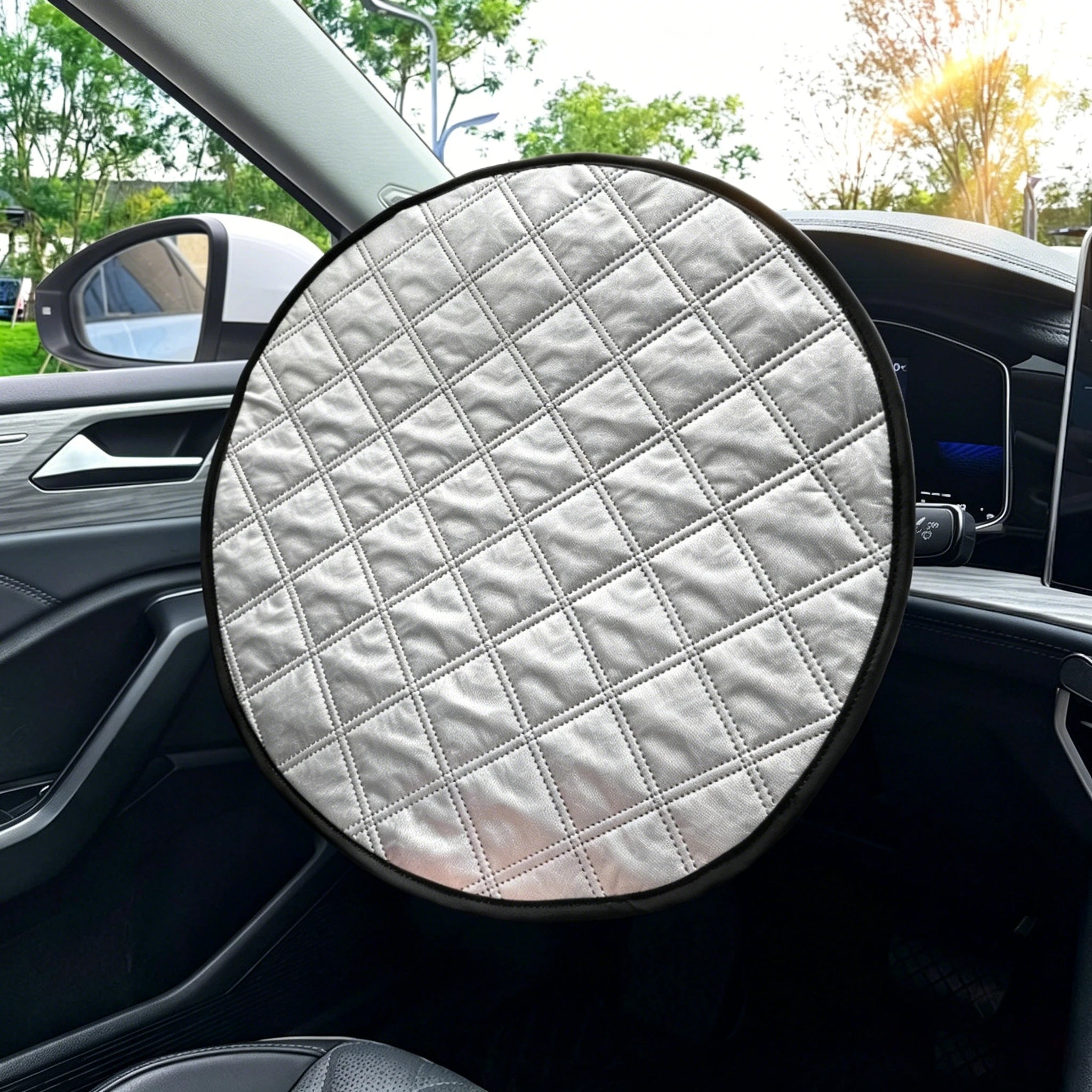 A round car steering wheel cover with a quilted diamond pattern in light gray, shown installed on a car's steering wheel inside a vehicle.