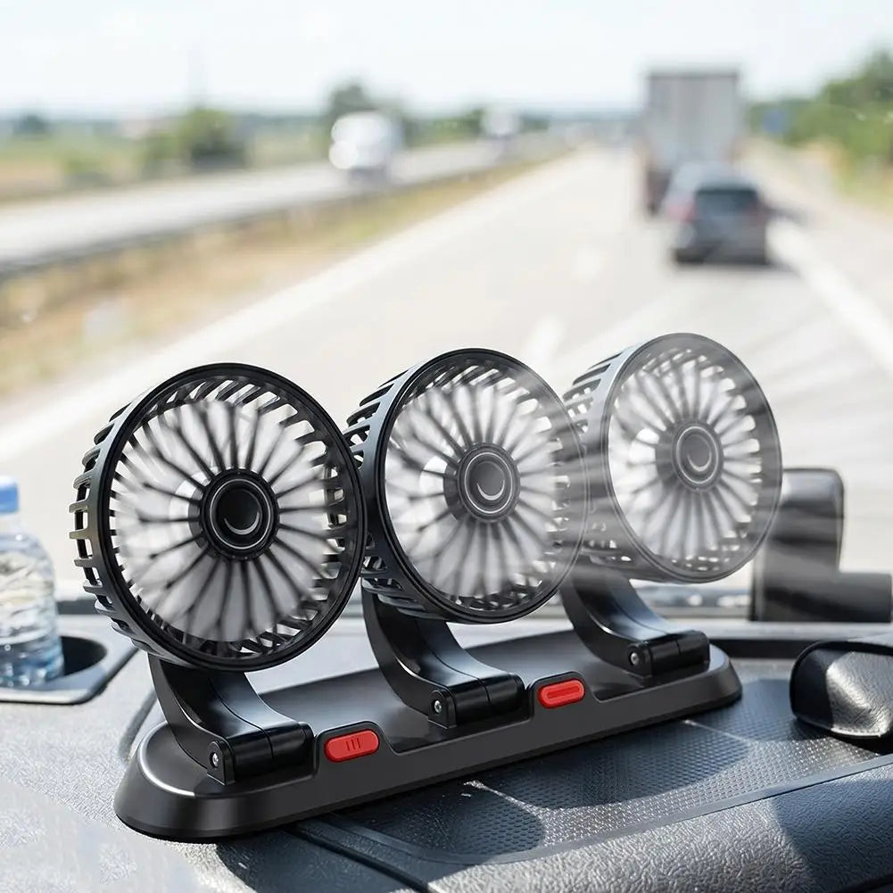 Three small black car fans mounted on a dashboard holder, photographed on a highway with blurred vehicles in the background.