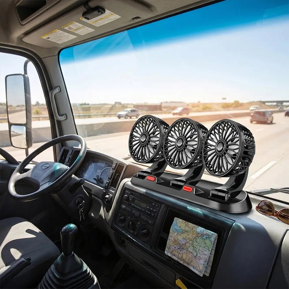 A set of four black portable truck cab fans mounted on the dashboard inside a vehicle, with a highway scene visible through the windshield.
